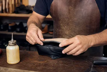Técnico colando a sola de um sapato, com materiais e cola ao lado.